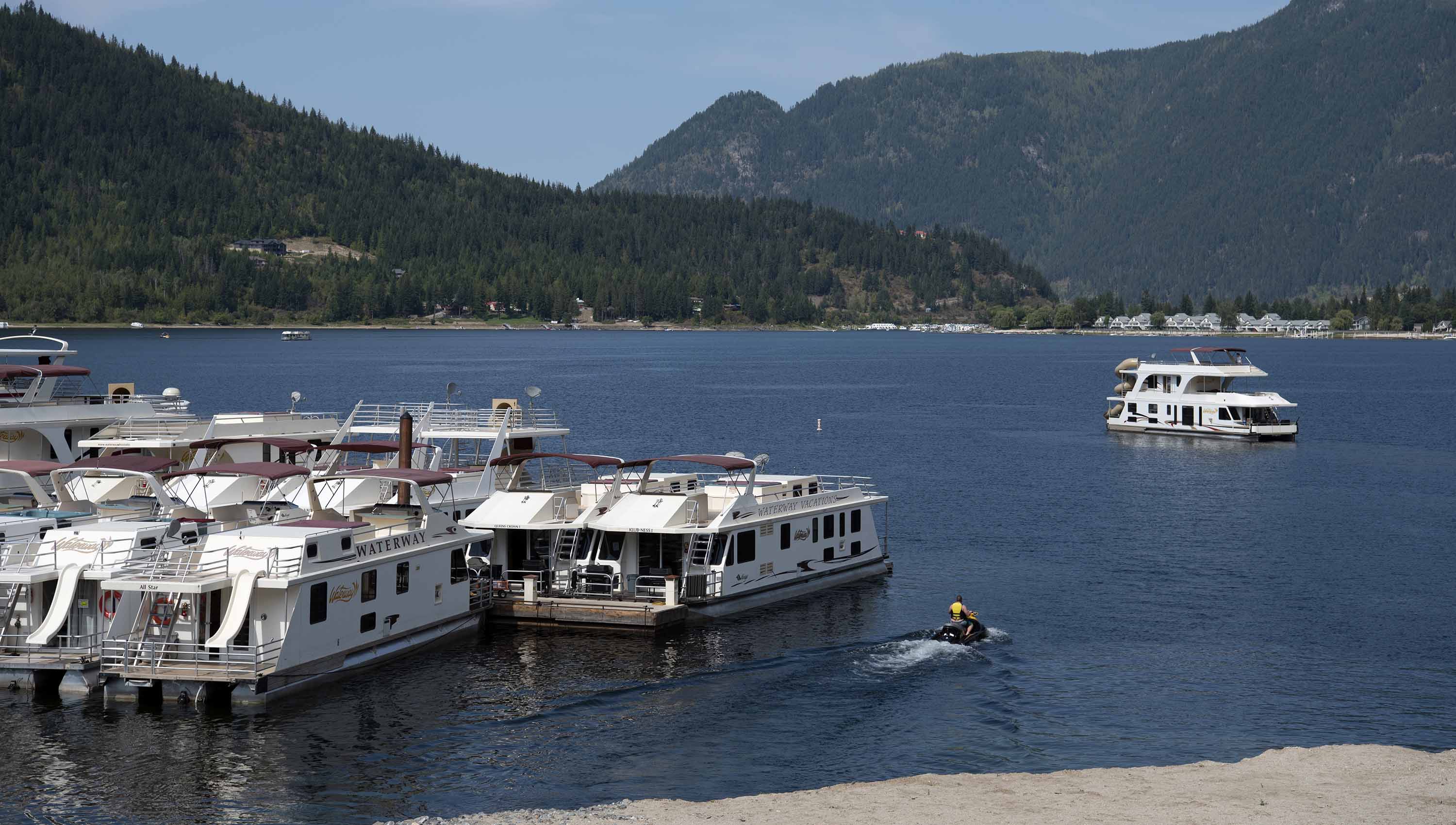 Sicamous Houseboats marine with houseboats docked at the marine and a seadoo leaving.
